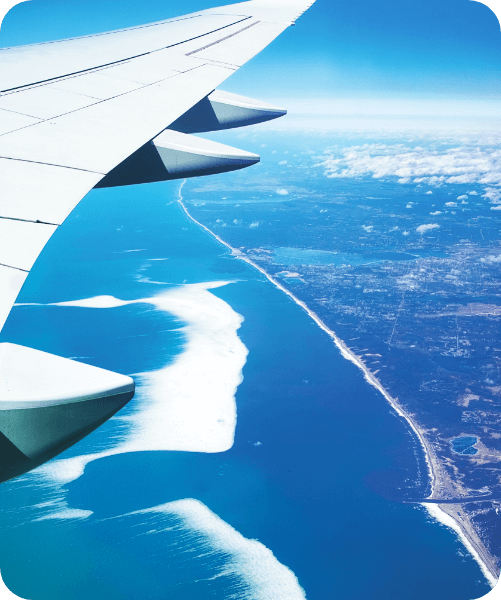 View of a plane wing flying from inside the plane looking over an ocean